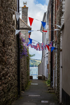 Narrow lane decorated flag garland with traditional britain red, white, blue colors in Salcombe, Devon, UK