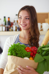 Young woman holding grocery shopping bag with vegetables