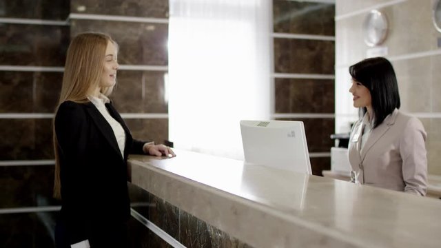 female traveller at the reception talking with staff excusing