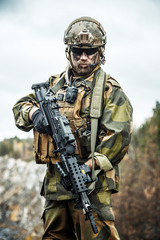 Norwegian Rapid reaction special forces FSK soldier patrolling in the forest. Painted face, combat...