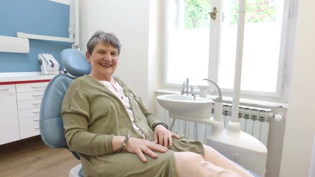 Smiling elderly female patient sitting in the dental chair 