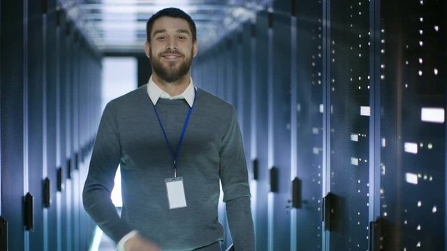 Male Server Engineer Working on a Laptop in Data Center, Closes Notebook and Smiles. Shot on RED EPIC-W 8K Helium Cinema Camera.