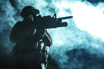 Black silhouette of soldier with grenade launcher in the smoke moving in battle operation. Back...