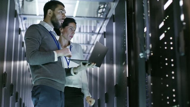 Male and Female Server Engineers Work on a Laptop in Data Center. He Opens Server Cabinet. Shot on RED EPIC-W 8K Helium Cinema Camera.