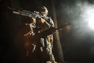 Image of soldiers in the smoke moving in battle operation. Back light, dark night, forest