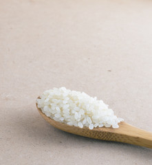 Rice in wooden spoon on background