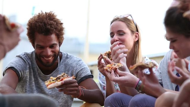 Group of multi-ethnic friends at a party eating pizza, graded