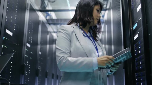 Female Asian IT Engineer Taking Hard Drives off the Crash Cart and Putting Them into Rack Server. She's Working in Data Center. Shot on RED EPIC-W 8K Helium Cinema Camera.