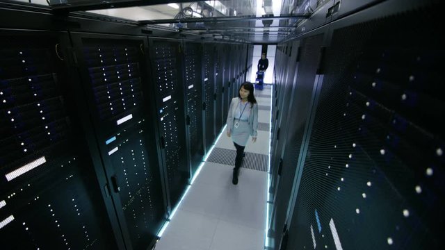 Security Camera Footage of Asian Female IT Specialist and Caucasian Male Server Engineer Who Pushes Crash Cart. They're Working in Big Data Center. Shot on RED EPIC-W 8K Helium Cinema Camera.