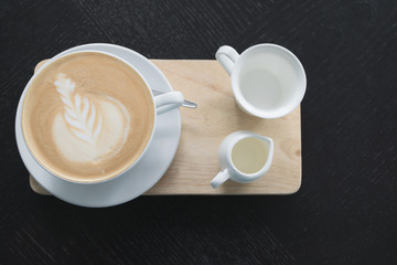 White cup of coffee on wooden table in the coffee shop.