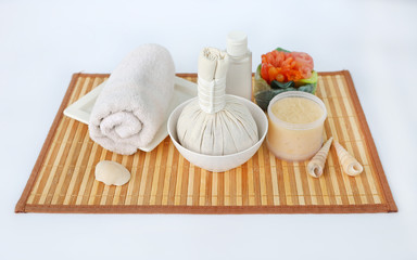 Spa herbal compressing ball with towels and Salt Scrub, Spa concept on bamboo weave mat against white background
