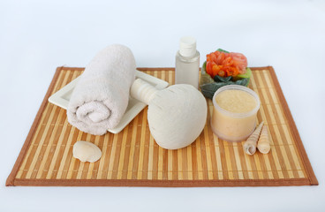 Fototapeta na wymiar Spa herbal compressing ball with towels and Salt Scrub, Spa concept on bamboo weave mat against white background
