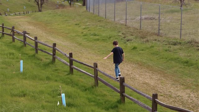 Little boy playing and climbing on an old wooden fence 4k Aerial stock video clip 