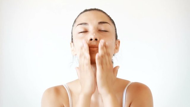 Portrait of beautiful brunette woman applying cream on her face