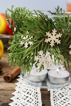 Decorative christmas jar for candles with thuja twigs wreath and wooden stars.