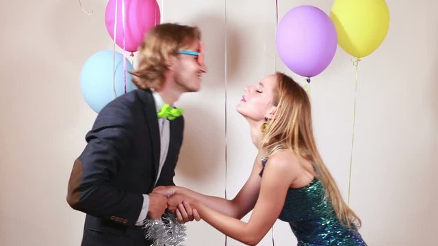 Cute couple playing tug of war with shiny brace string in photo booth 