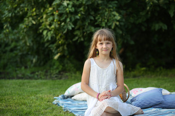 young teen girl sitting and smiling on a blanket in nature