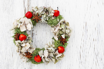 Christmas door wreath with moss, paradise apples and dry hortensia flowers.