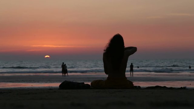 GOA, INDIA - 21 JANUARY 2015: Man sitting on beach at sunset playing music to the sun.