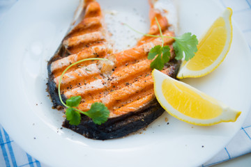 grilled fish with greens and lemon wedges