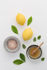 Homemade skincare concept, bath salt, lemon, honey dipper and mint on white wooden background from top view. Good for background and space.