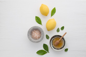 Homemade skincare concept, bath salt, lemon, honey dipper and mint on white wooden background from top view. Good for background and space.