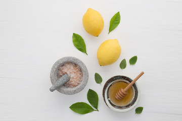 Homemade skincare concept, bath salt, lemon, honey dipper and mint on white wooden background from top view. Good for background and space.