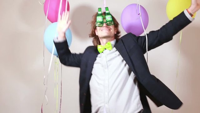 Young handsome man with funny beer sunglasses dancing in party photo booth