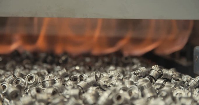 Metal parts on a conveyor belt during hardening process