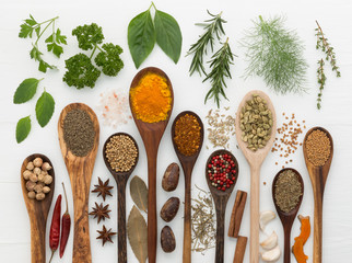 various kinds of spices and herbs with wood spoon on white background.