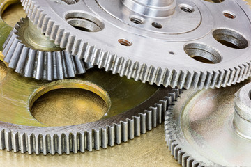 set of industrial gear cogwheels on scratched brass metal background