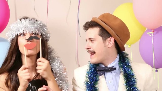 Cute young couple having fun in party photo booth