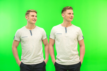 The two attractive twin stand on the green background