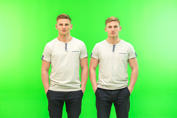 The two handsome twin stand on the green background