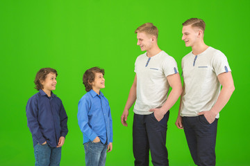 Obraz premium The four attractive brothers stand on the green background