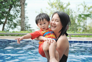 Fototapeta na wymiar Mother and her son Playing in the pool