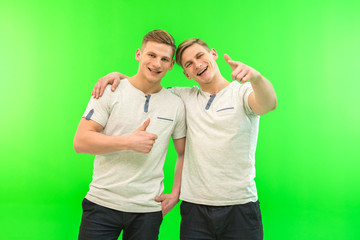 The two happy twin brother gesture on the green background