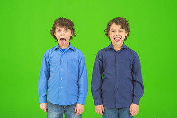 The two funny twin kids grimace on the green background