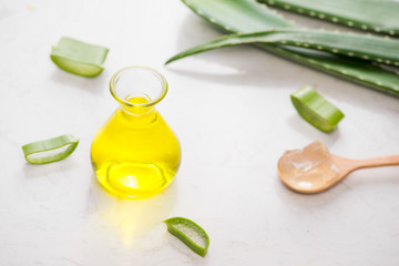 Aloe vera essential oil and aloe leaves on a white background.