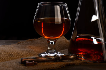 glass, carafe with cognac, whiskey and key on wooden table