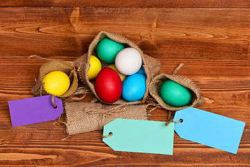 painted easter colorful eggs in burlap sack on wooden background