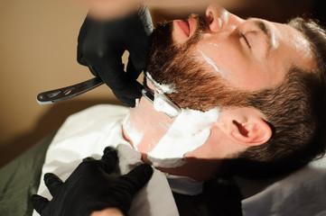 Obraz na płótnie Canvas Master cuts hair and beard of men in the barbershop