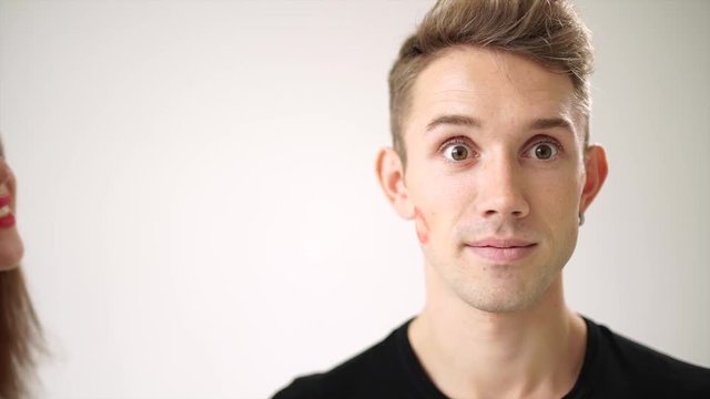 The young man is overjoyed after the kiss girls. On his cheek left a bright red imprint of lips