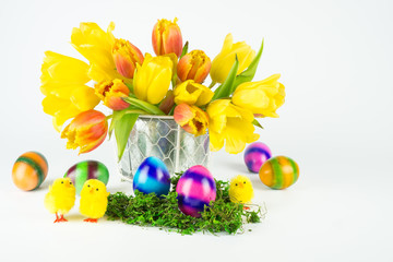 Ein Strauß roter und gelber Tulpen mit zwei Ostereiern und drei kleinen Küken auf grünem Moos, isoliert auf weißem Hintergrund,