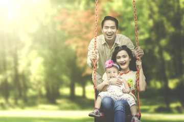 Asian family playing on swing