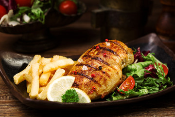 grilled chicken breast with green salad and french fries.