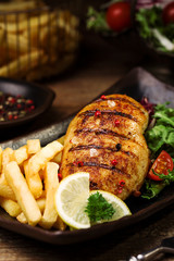grilled chicken breast with green salad and french fries.