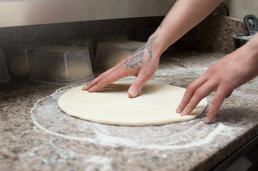 Close-up of male hands baker kneads raw pizza dough. Fast food. Pizza delivery. Baking.