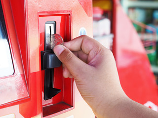 human hand inserting coin in vending machine