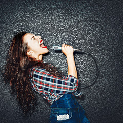 Karaoke party. Time to sing! Crazy casual curly chic girl singing with microphone. Studio shot - 141952572